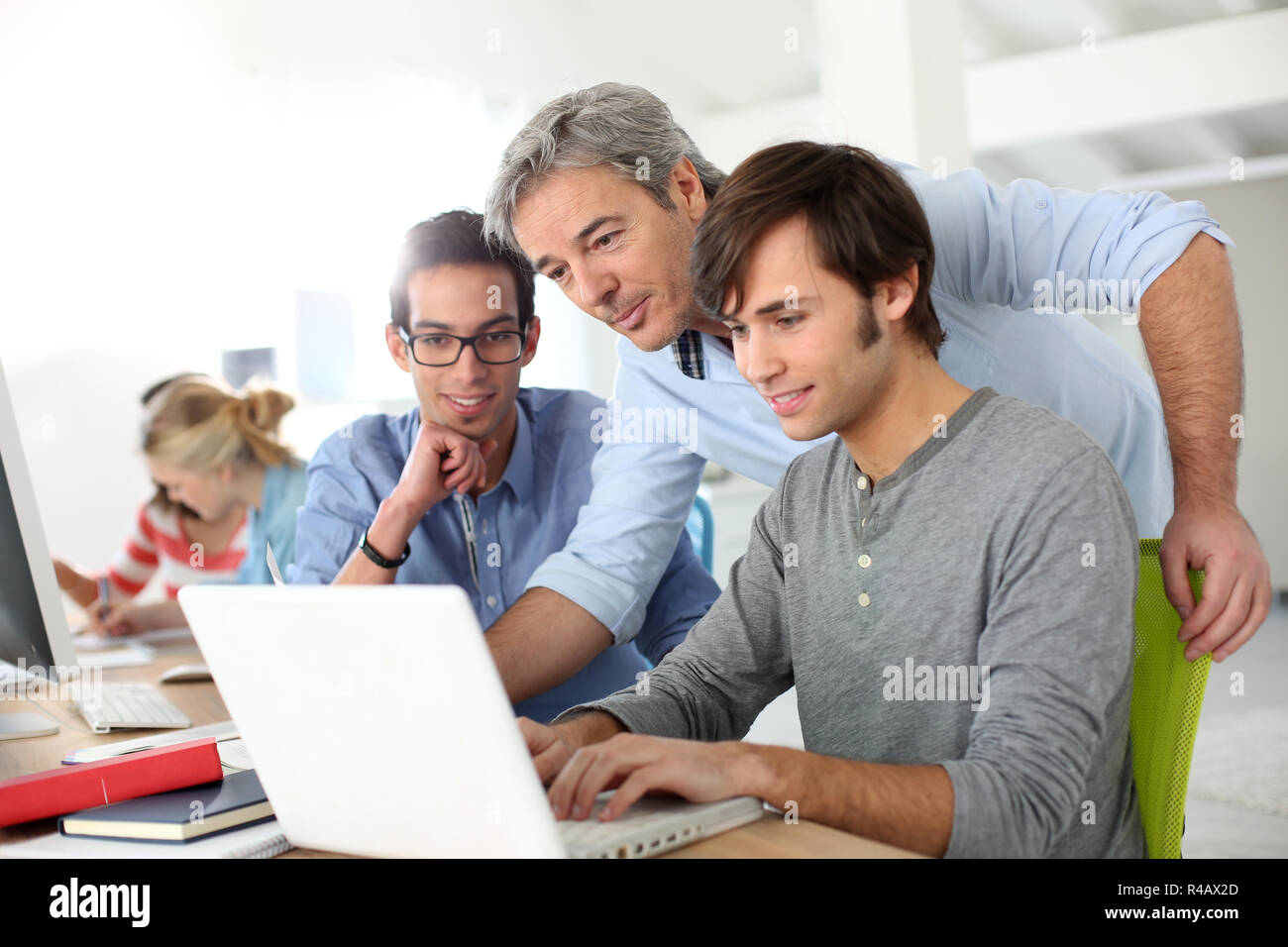 Students in class with teacher helping with work Stock Photo