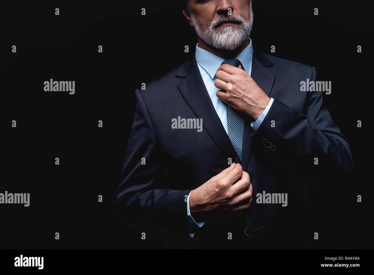 Man in a suit fixing his tie Stock Photo - Alamy