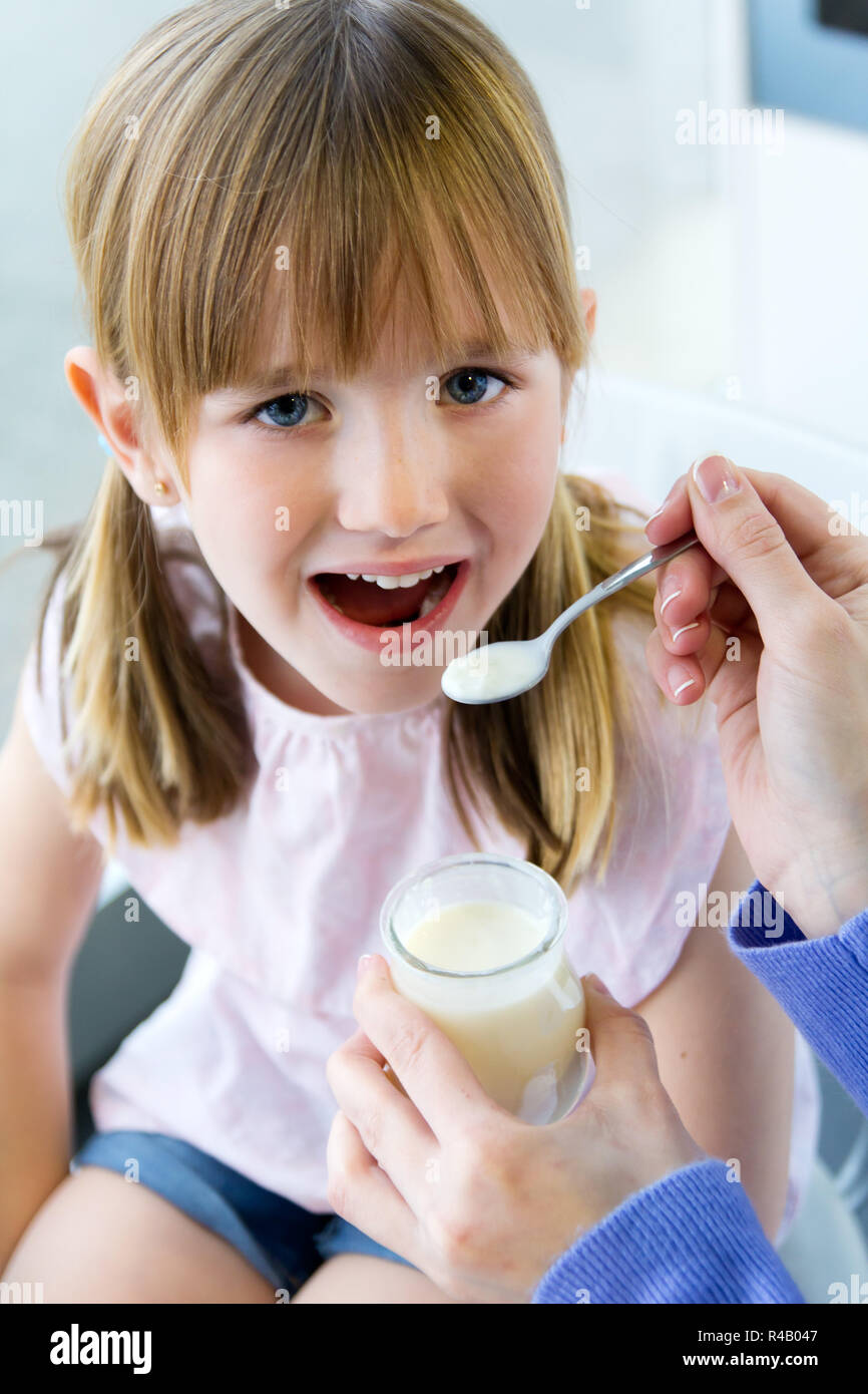 a young woman and little girl eating yogurt in the kitchen Stock Photo