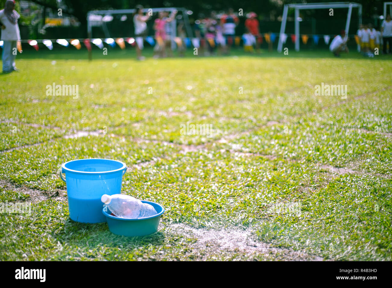 Bucket of water, a cup and a basin for children games on the field