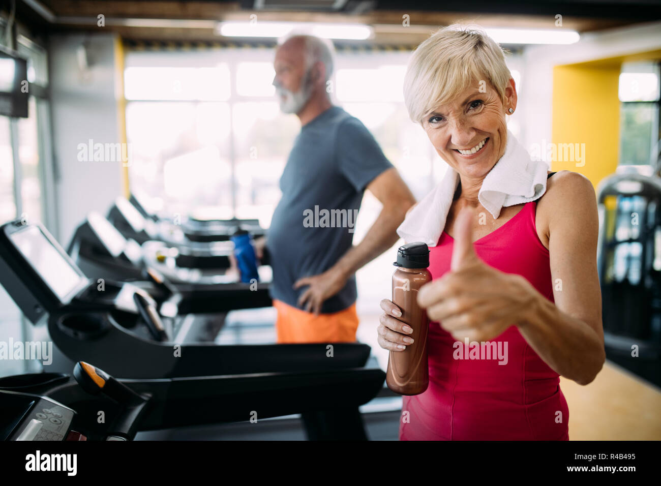 Senior people running in machine treadmill at fitness gym club Stock Photo