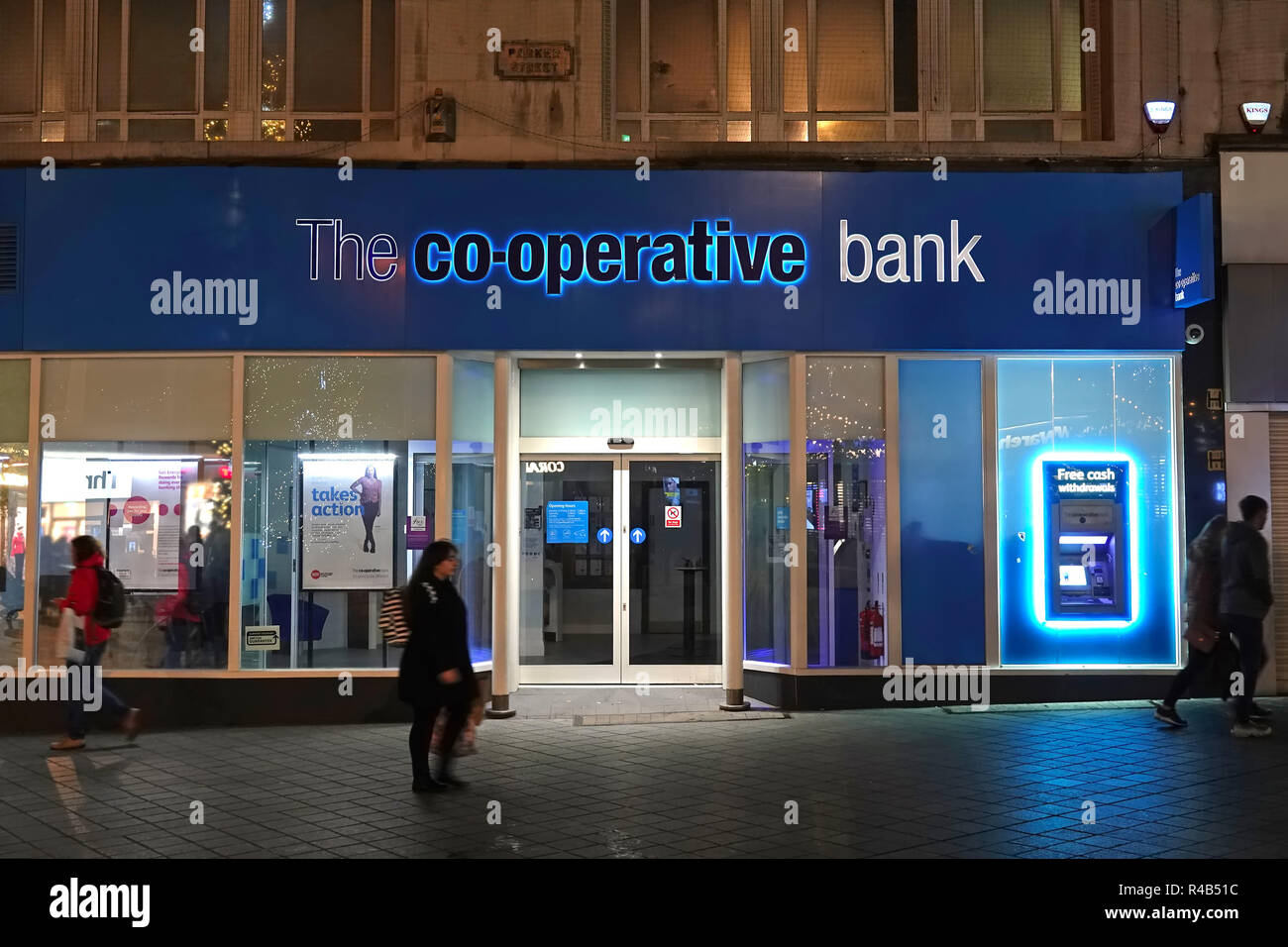 People walking past a branch of The Co-Operative Bank in Parker St Liverpool UK at night 2018 Stock Photo