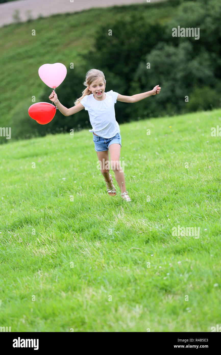 Little girl running in field with balloons in one hand Stock Photo - Alamy