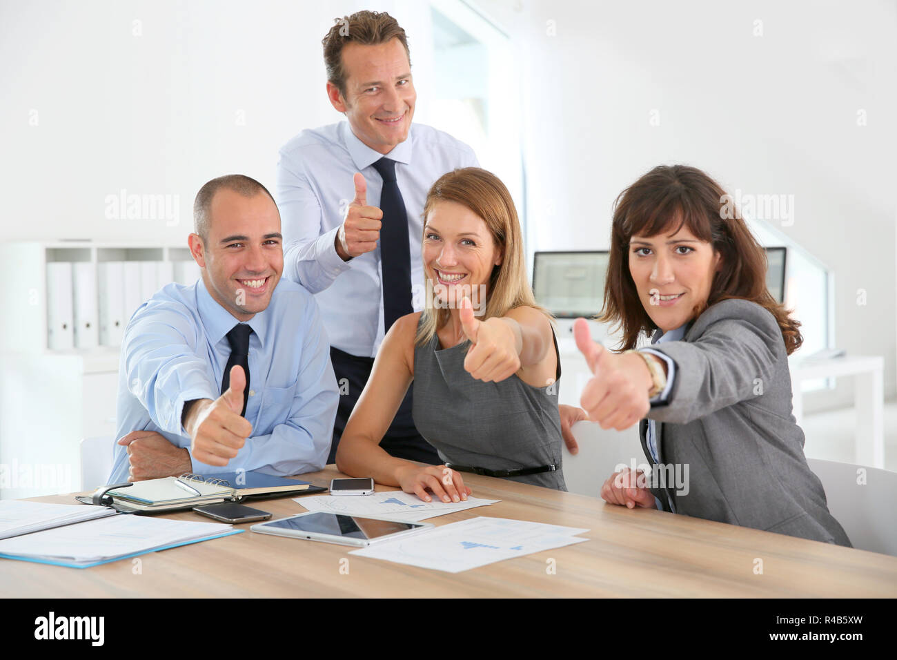 Cheerful business team showing thumbs up Stock Photo - Alamy