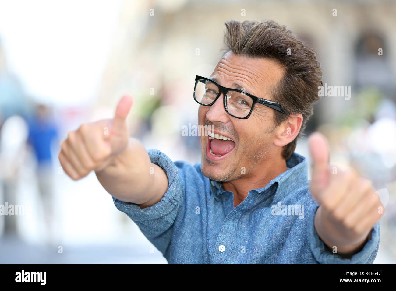 Cheerful guy with eyeglasses showing thumbs up Stock Photo - Alamy