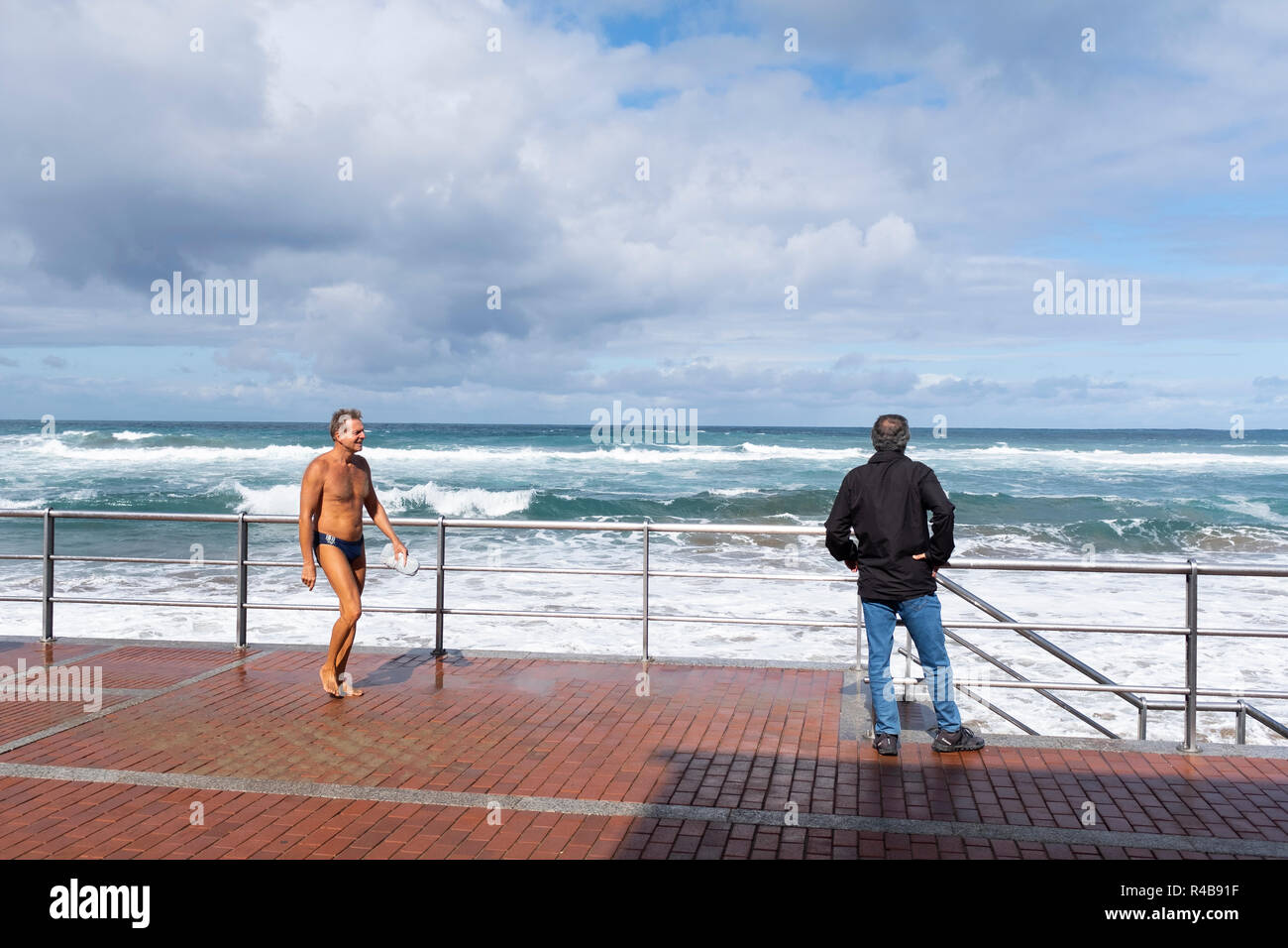 a dressed man and another in a swimsuit on the beach Stock Photo