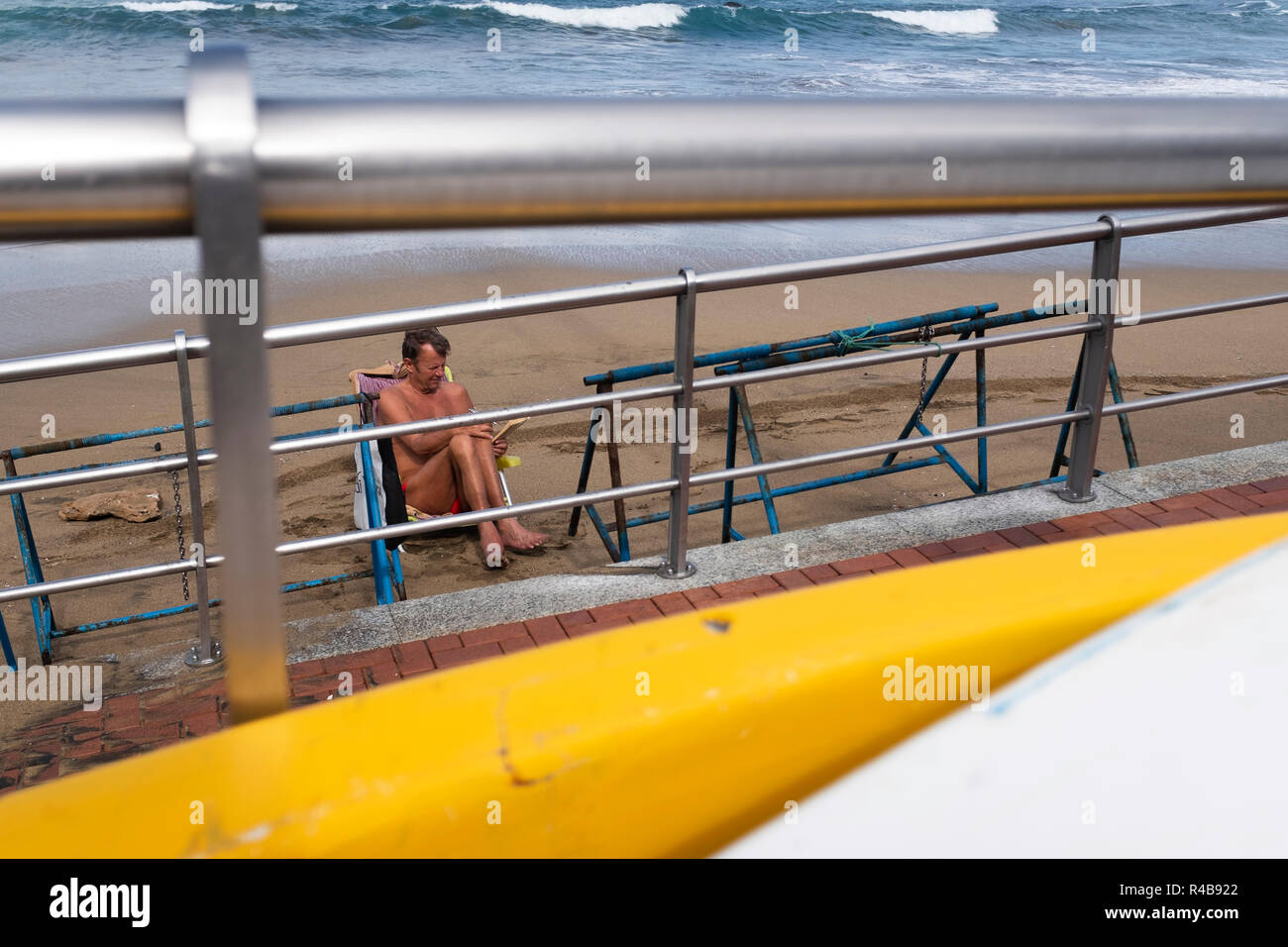 a man reading a book on the beach of Las Canteras, Las Palmas de Gran Canaria Stock Photo