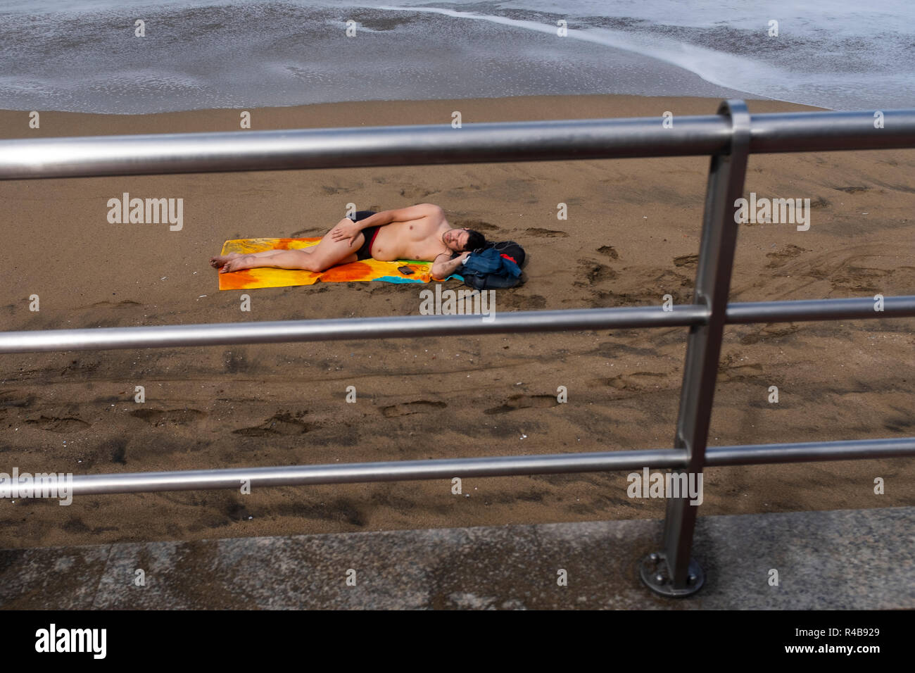 a man lying on the sand on the beach of Las Canteras, Las Palmas de gran Canaria Stock Photo