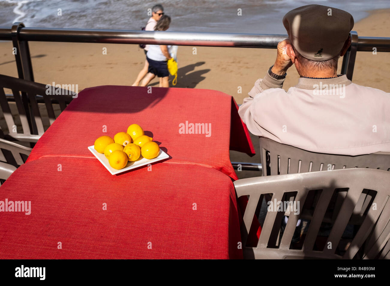a man on a terrasa observes people on the beach Stock Photo