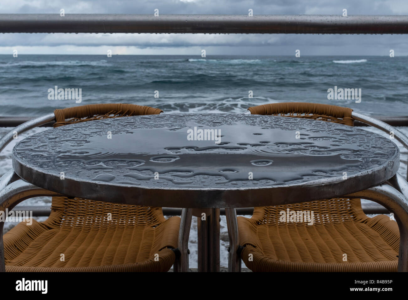 the chairs and tables of a terrace wet because of the rain on the beach of Las Canteras in Las Palmas de Gran Canaria, Spain. Stock Photo