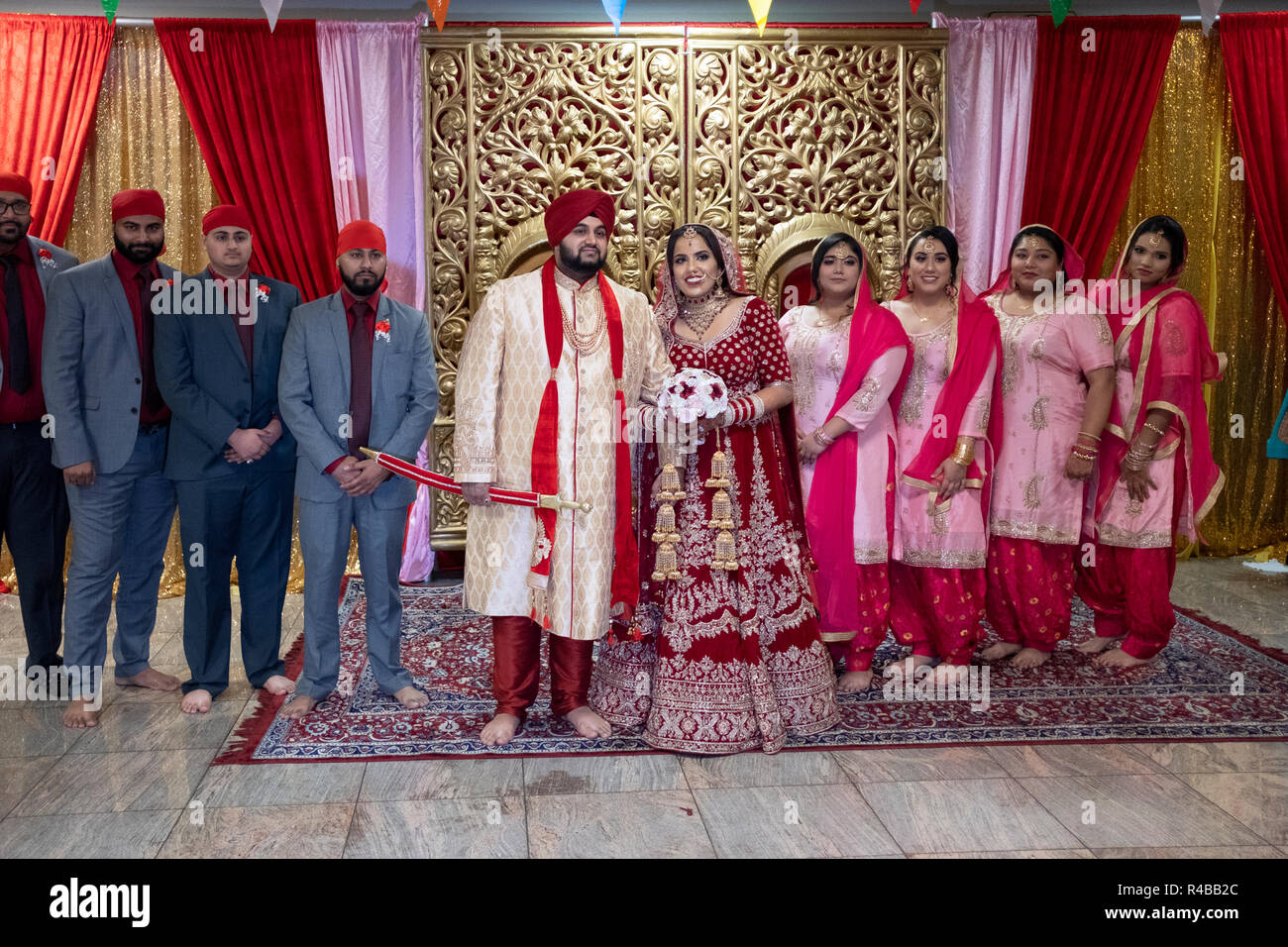 Just after their wedding, a Sikh couple poses with their bridal party at a temple in Queens, New York City. Stock Photo