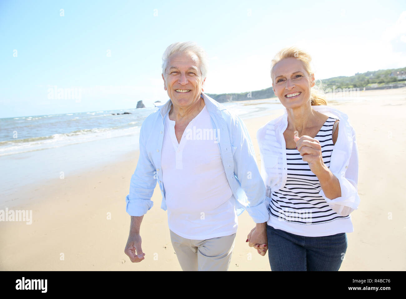 Senior couple running on a sandy beach Stock Photo
