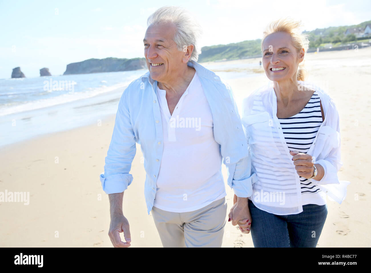 Senior couple running on a sandy beach Stock Photo