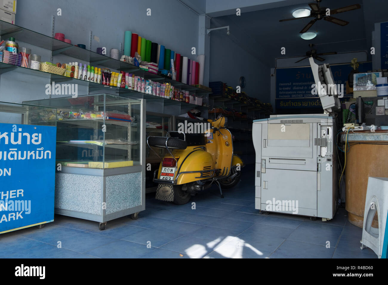 A yellow Vespa scooter is casually parked inside an office supply store in Hat Yai, Thailand. Stock Photo
