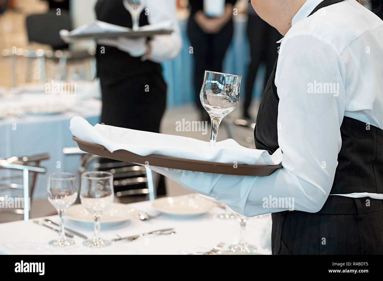Waitress dressed in the uniform serving a set of wine glasses Stock Photo