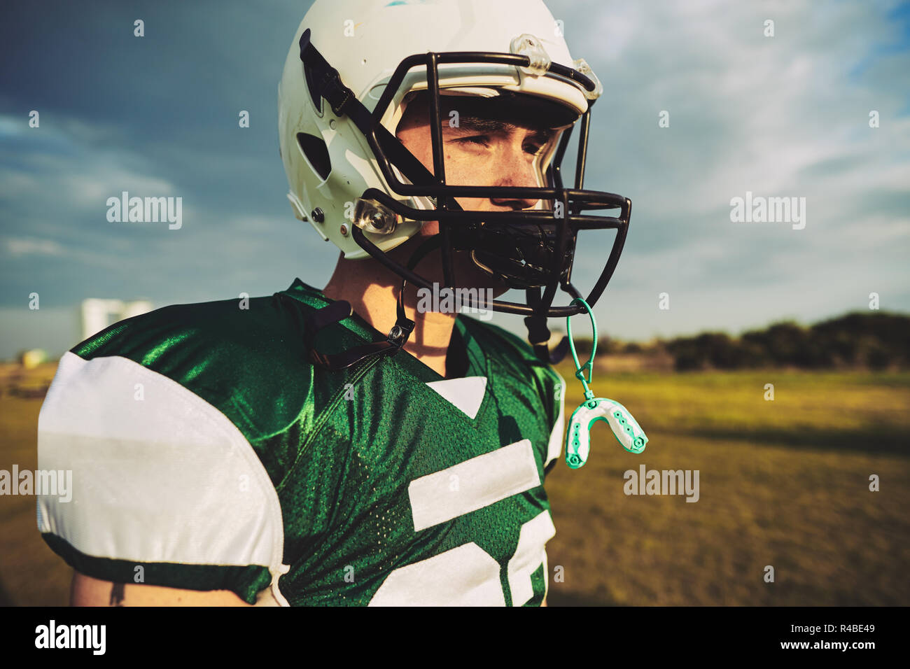 Young American football player taking a break with his mouth guard hanging from his helmet during a team practice session Stock Photo