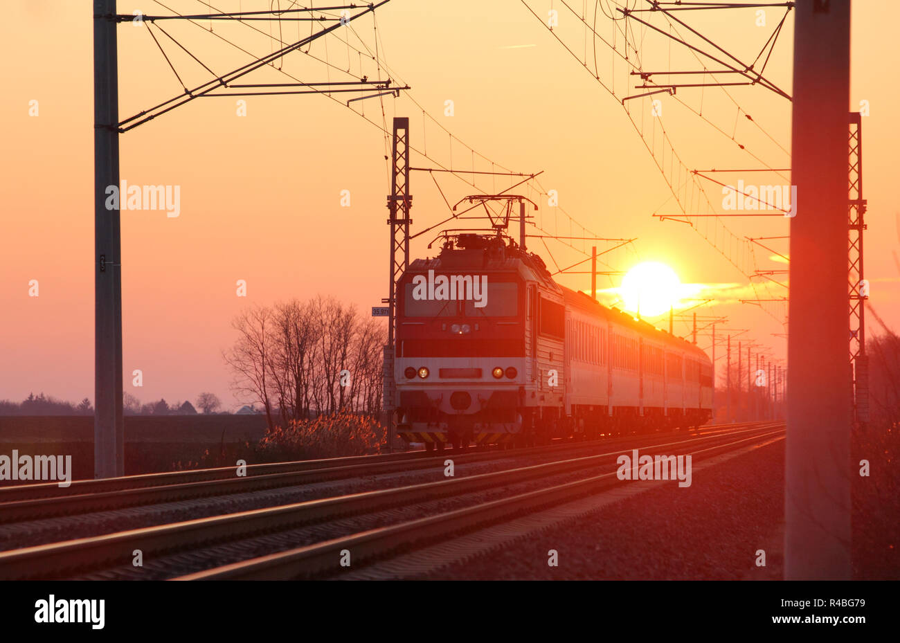 Passenger train on railway at sunset Stock Photo