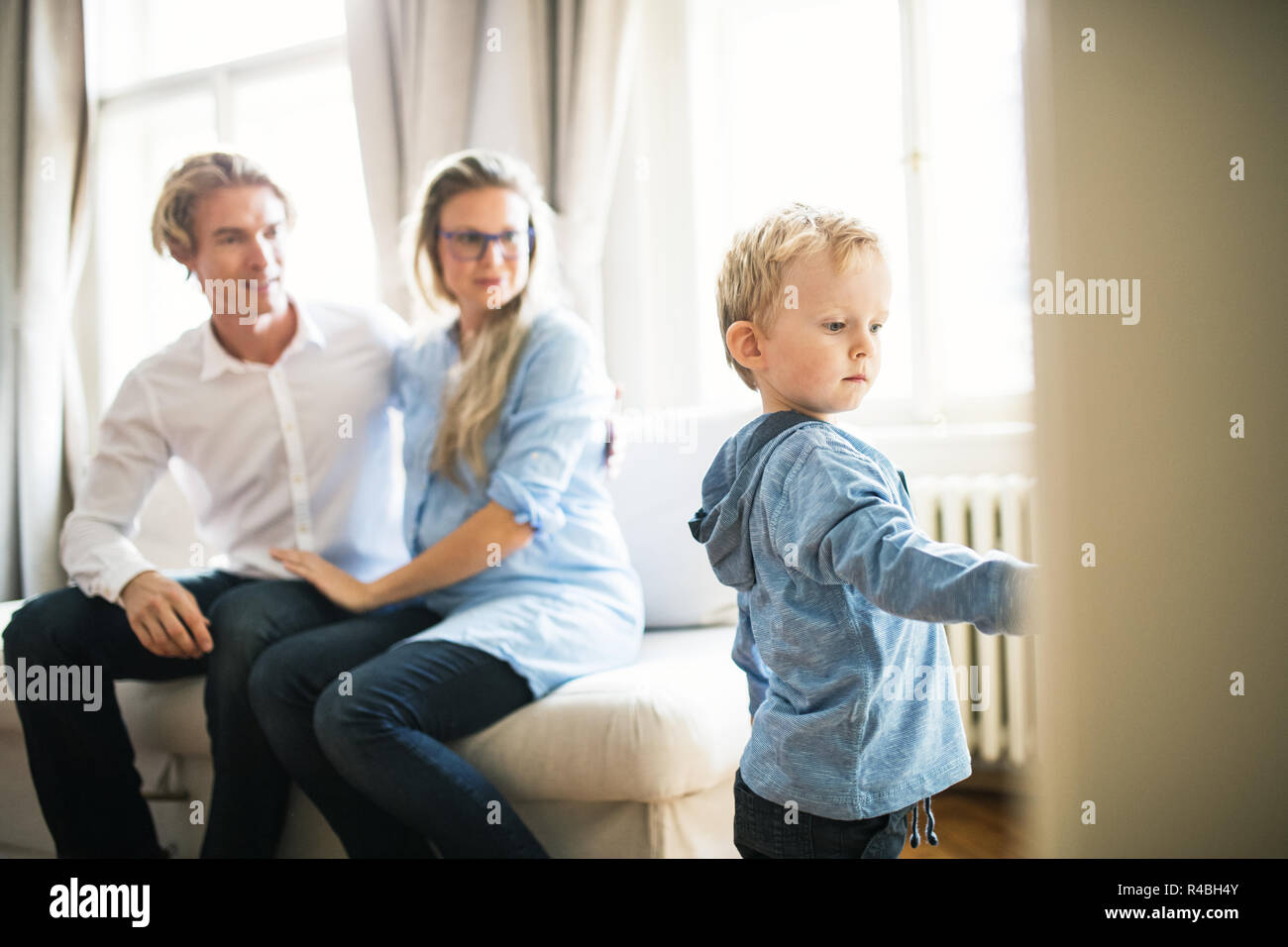 Young parents looking at their toddler son inside in a bedroom. Stock Photo