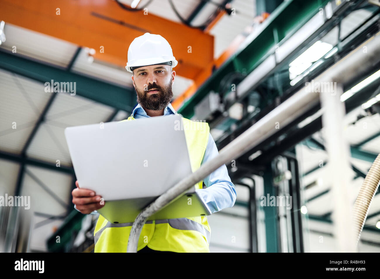 An industrial man engineer with laptop in a factory, working. Stock Photo