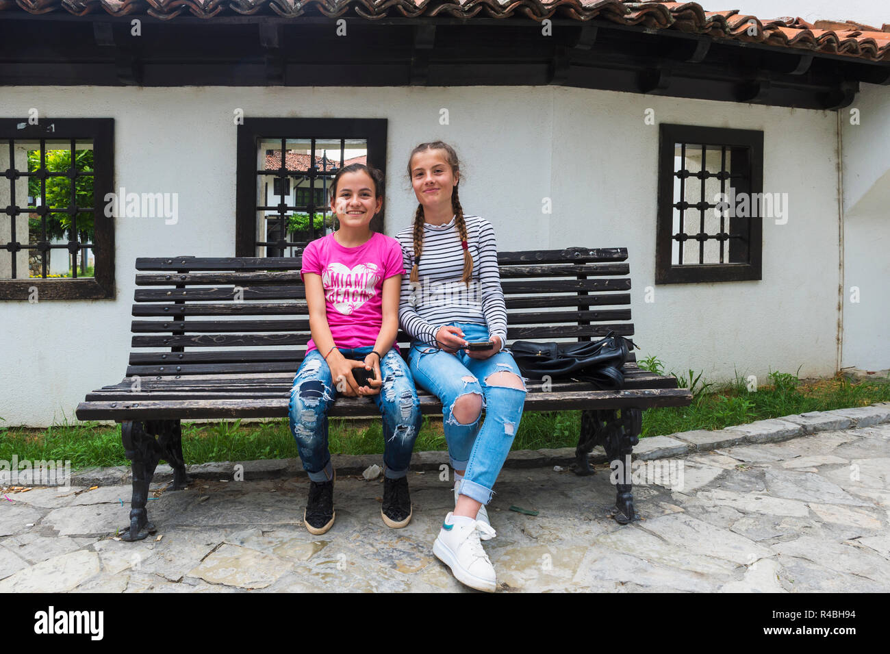 Two girls seated in front of the Building of League for the Defense of the Rights of the Albanian Nation or League of Prizren, Kosovo Stock Photo