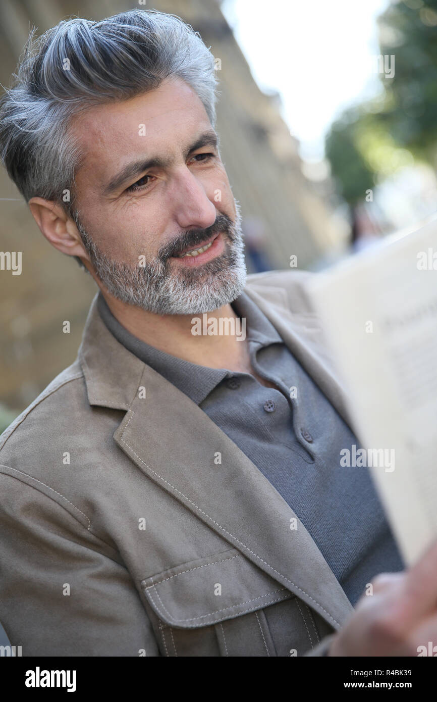 Mature man in town reading newspaper Stock Photo - Alamy