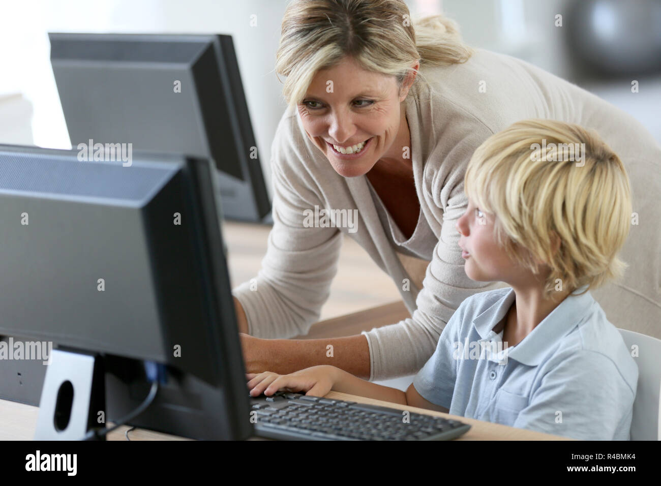 Teacher with schoolboy studying on computer Stock Photo - Alamy