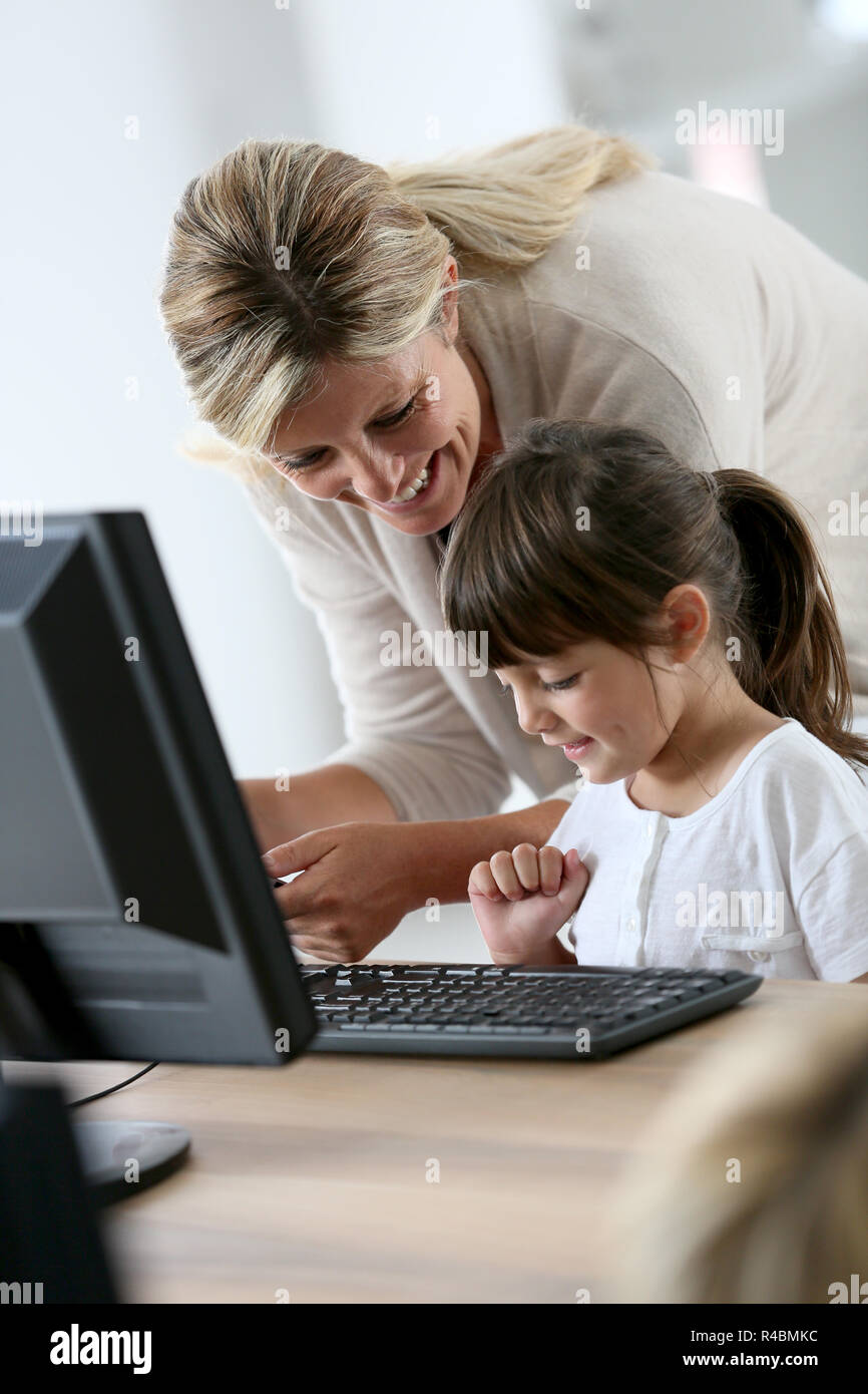 Teacher with little girl in class using computer and tablet Stock Photo ...