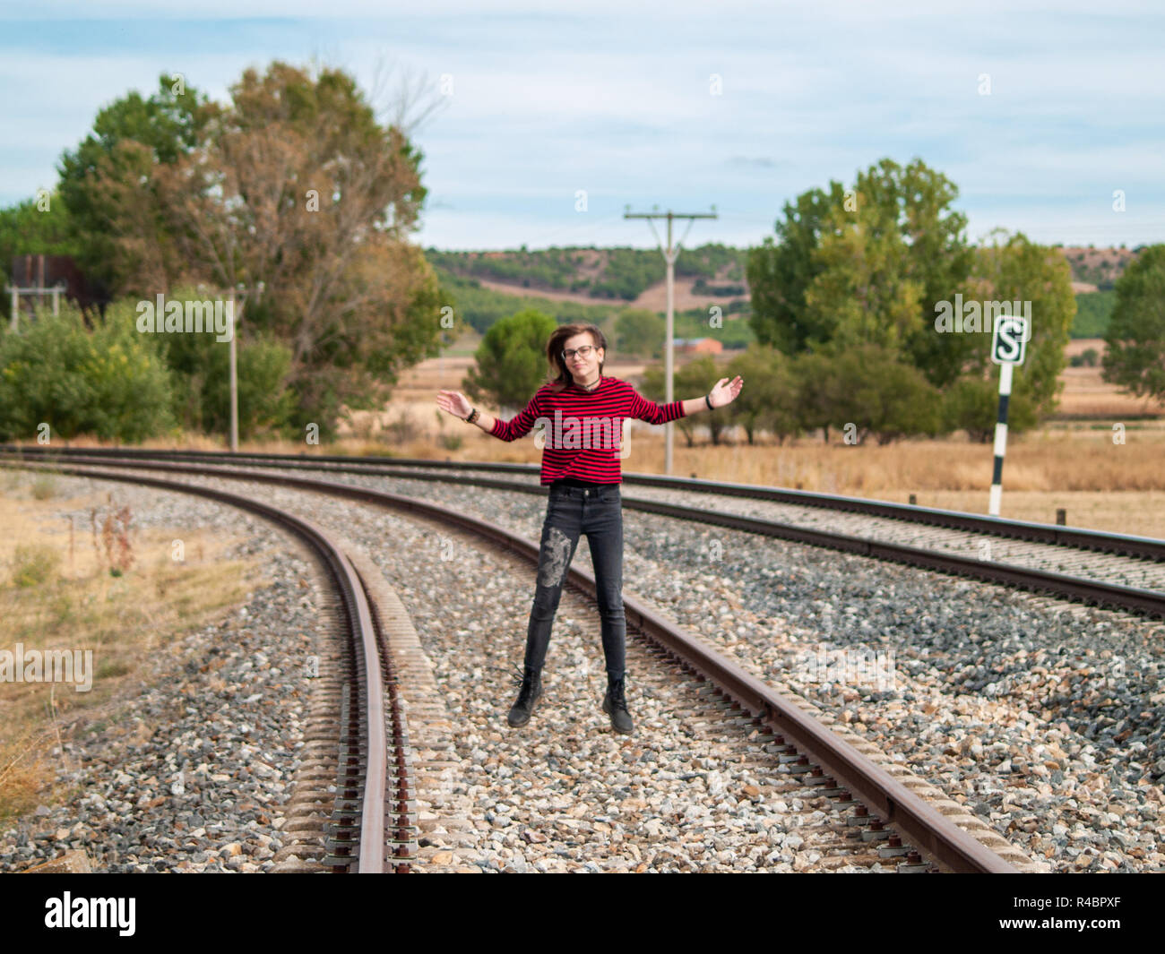 A teenage girl jumping on the train tracks. Concept of freedom and joy