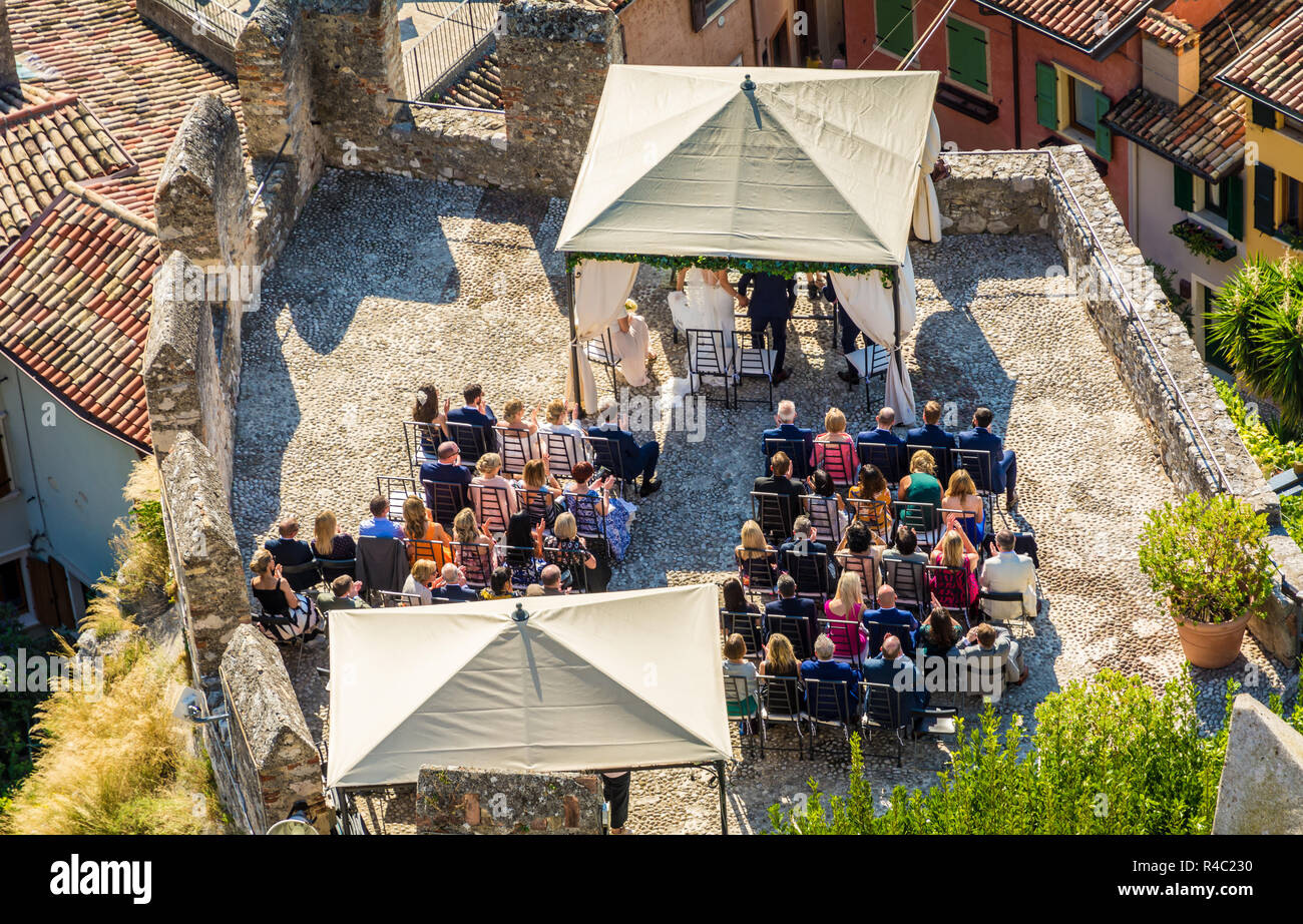 A couple celebrates the outdoor wedding in the Scaliger Castle of the medieval town of Malcesine on Lake Garda, northern Italy. view from above Stock Photo