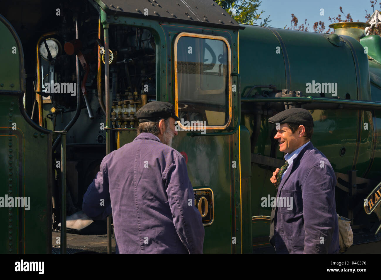Modified Hall Class steam locomotive 6960 Raveningham Hall at Bishops Lydeard Station on the West Somerset Railway with 2 of the engine crew talking Stock Photo