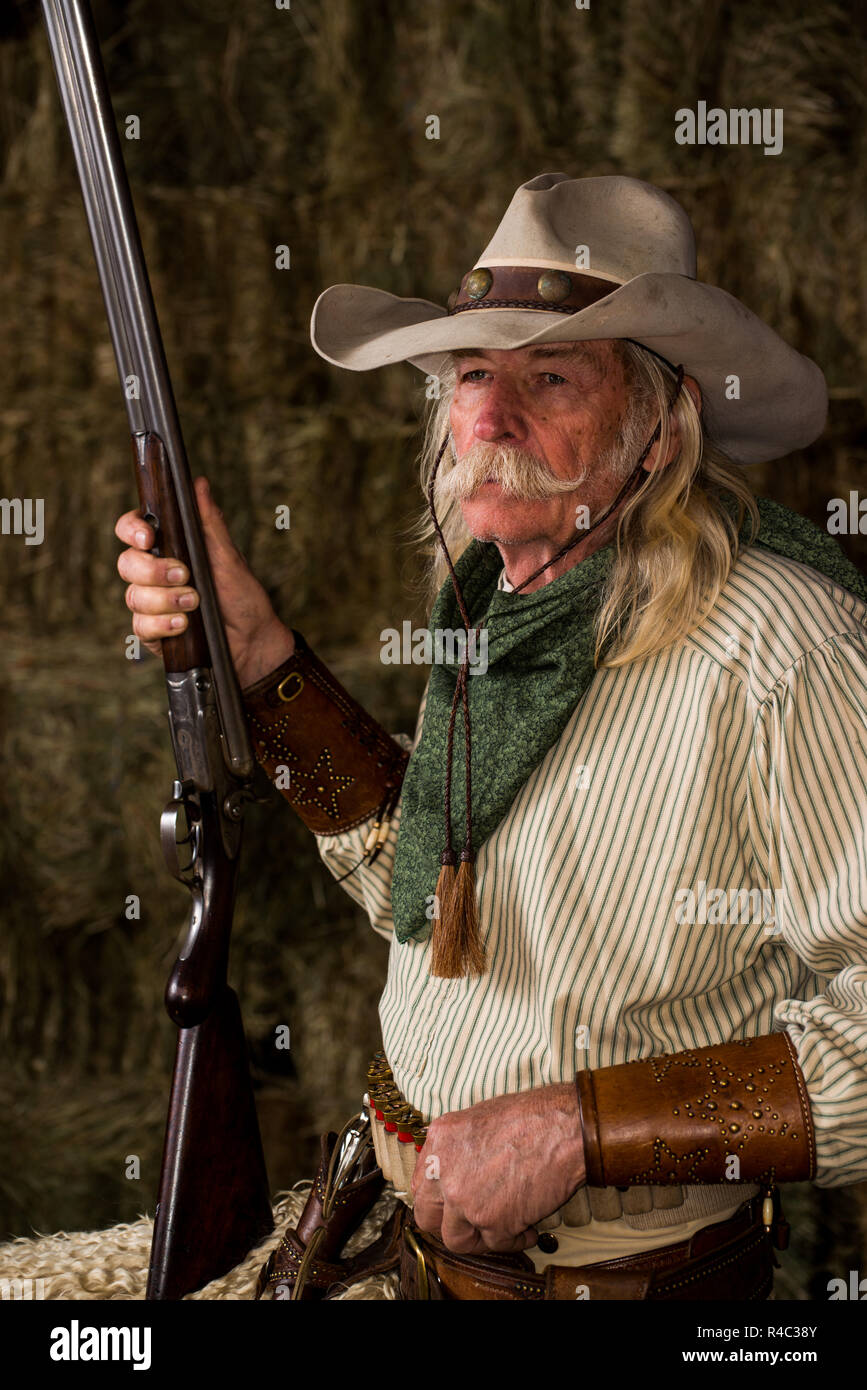 Western ranch cowboy wrangler with rifle, shotgun, bandanna, mustache and cowboy hat Stock Photo
