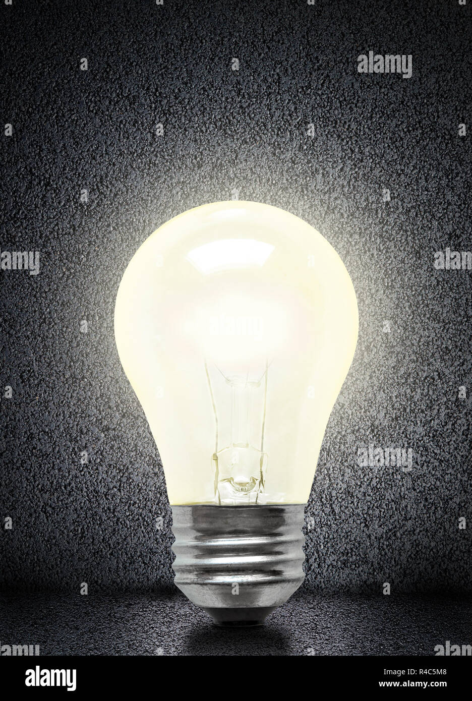 Glowing electrical incandescent light bulb isolated on asphalt background with copy space. Stock Photo