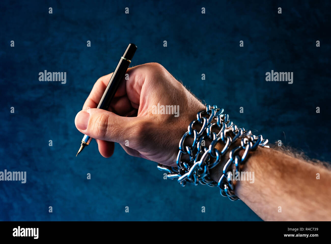 Freedom of the press and journalism, conceptual image with pen in male hand tied with chains, low key image Stock Photo