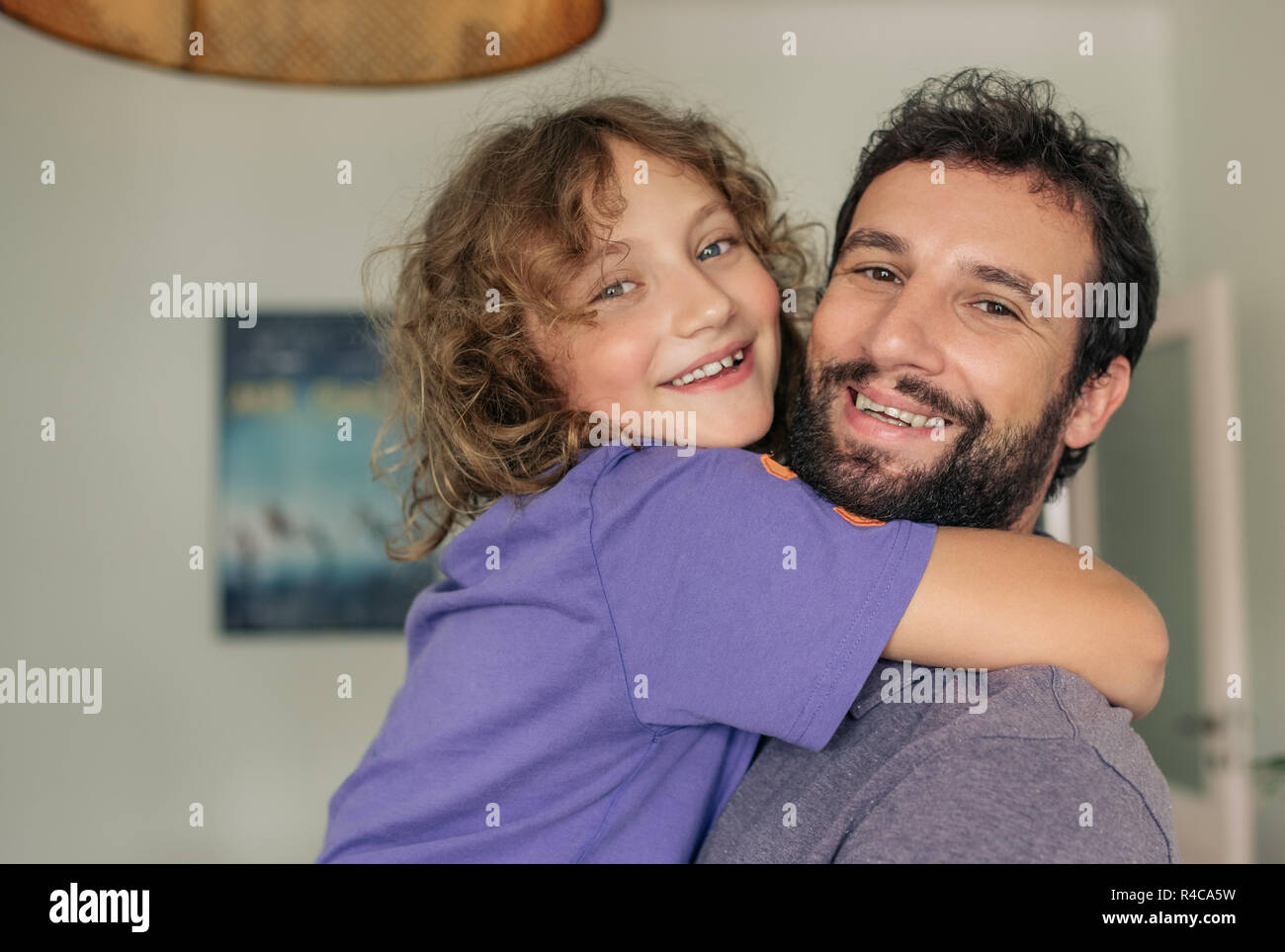 Content dad holding his son in his arms at home Stock Photo