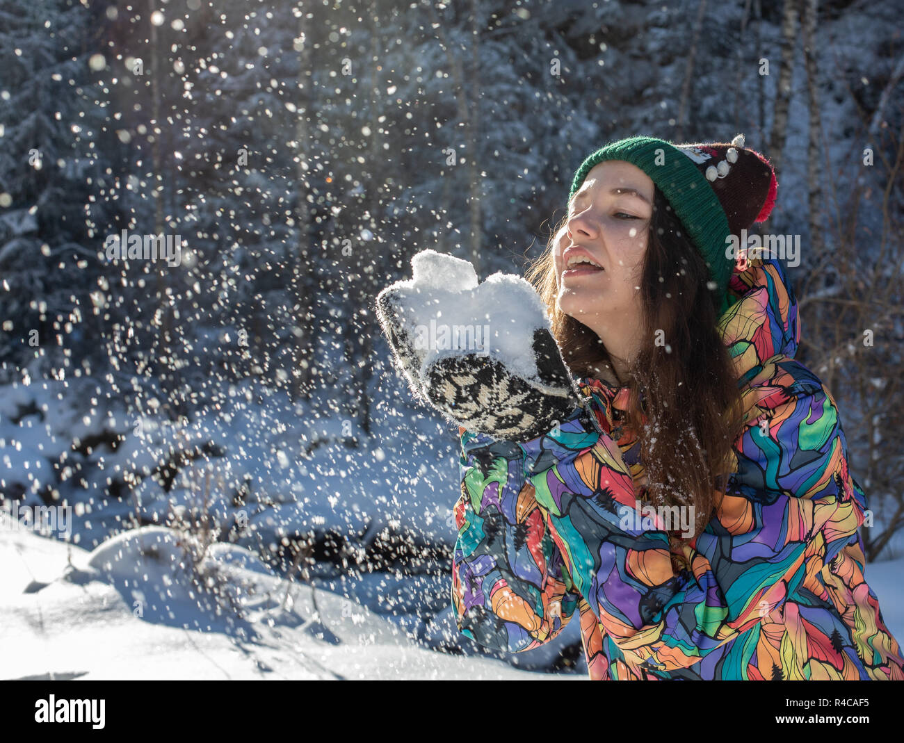 Happy winter fun woman throwing snow banner. Panorama crop of outdoor lifestyle girl playing in snow outside laughing in yellow coat, hat, gloves and scarf. Stock Photo