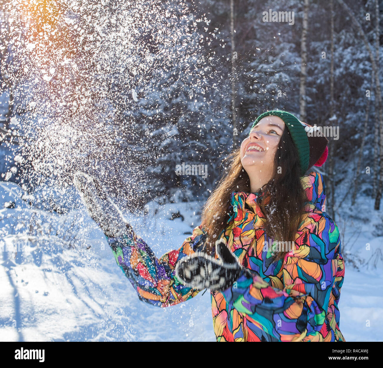 Happy winter fun woman throwing snow banner. Panorama crop of outdoor lifestyle girl playing in snow outside laughing in yellow coat, hat, gloves and scarf. Stock Photo