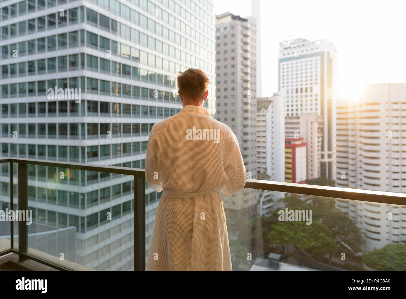 Young handsome man enjoying the view of the city from the balcon Stock Photo