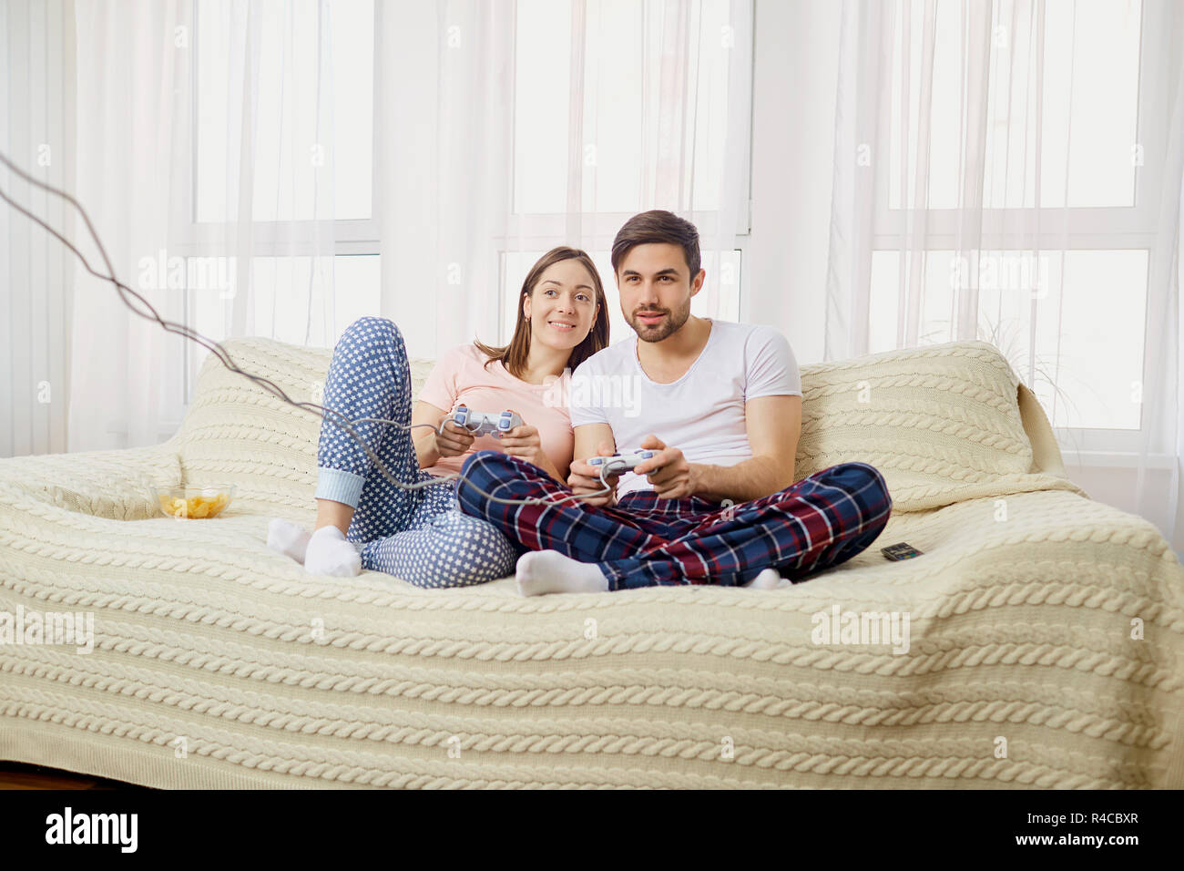 Husband and wife plays video games with joysticks in hands in th Stock Photo