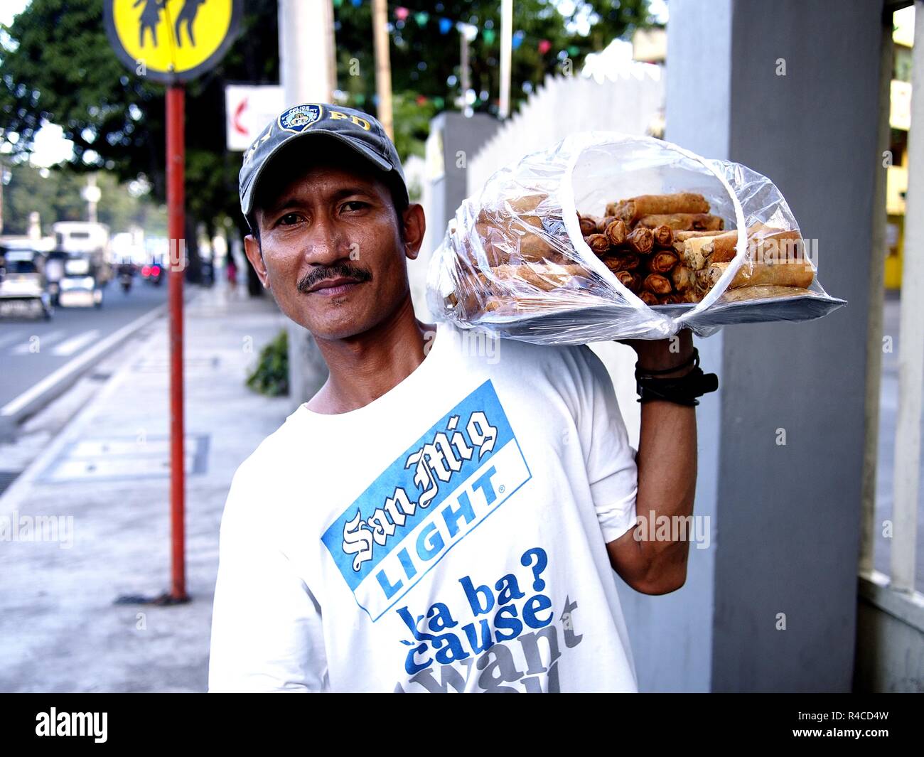 ANTIPOLO CITY, PHILIPPINES - NOVEMBER 24, 2018: A food vendor peddles deep fried vegetable rolls along a busy street. Stock Photo