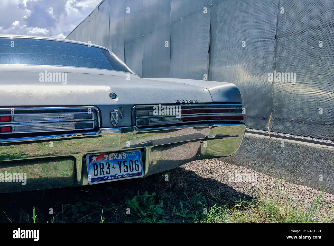 A vintage Buick sits in a lot next to a sheet metal wall in Marfa. Stock Photo