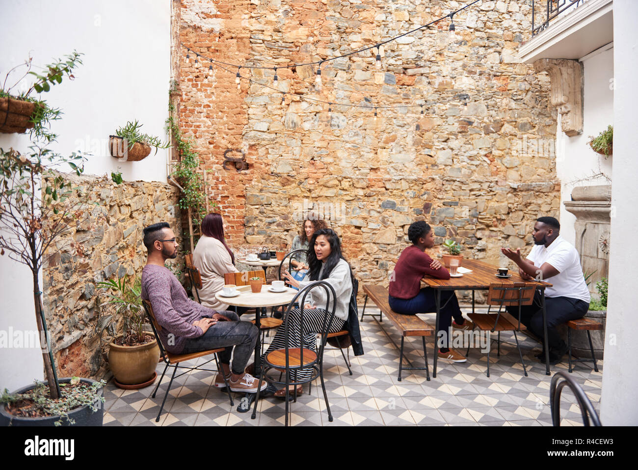 Diverse people talking over coffee in a trendy cafe courtyard Stock Photo