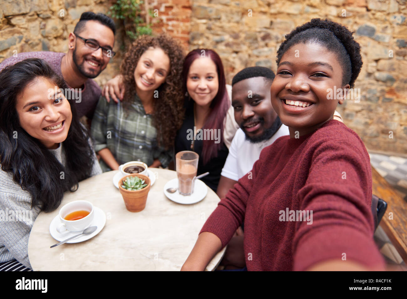 Diverse young friends taking selfies together in a cafe courtyard Stock Photo