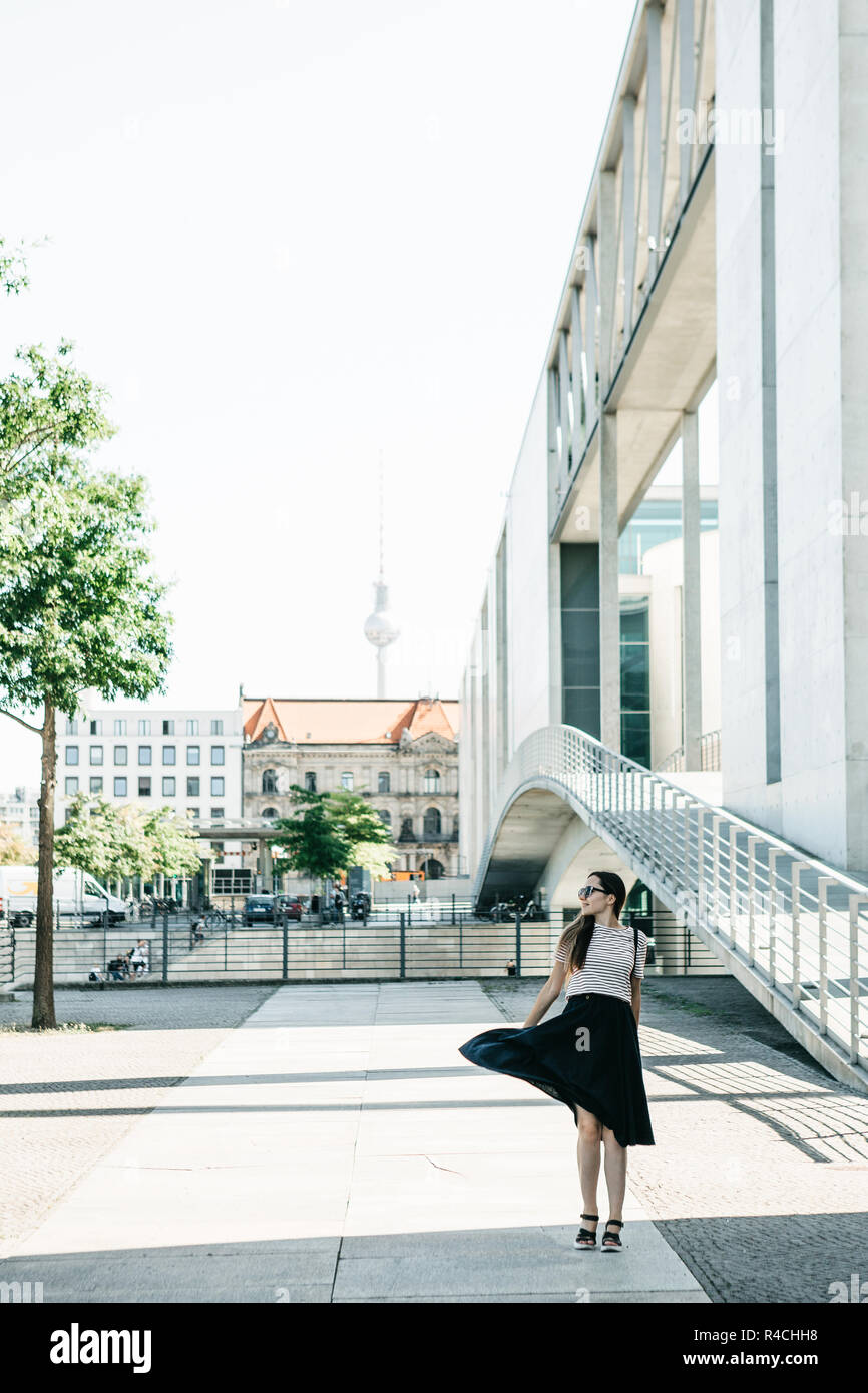 Beautiful fashionable girl in a skirt is dancing on the street in ...