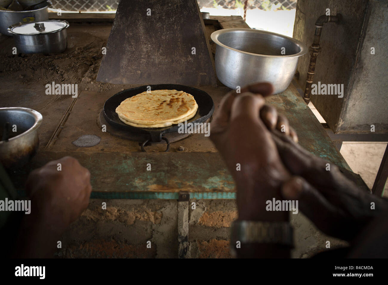 A man prepares food at the Community Cooker invented by Jim Archer used