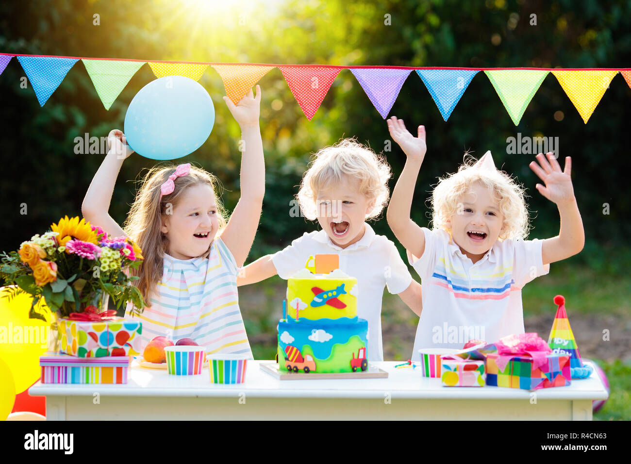Children blow candles on birthday cake. Kids party decoration and food. Boy and girl celebrating birthday of little brother. Transport and car kid eve Stock Photo