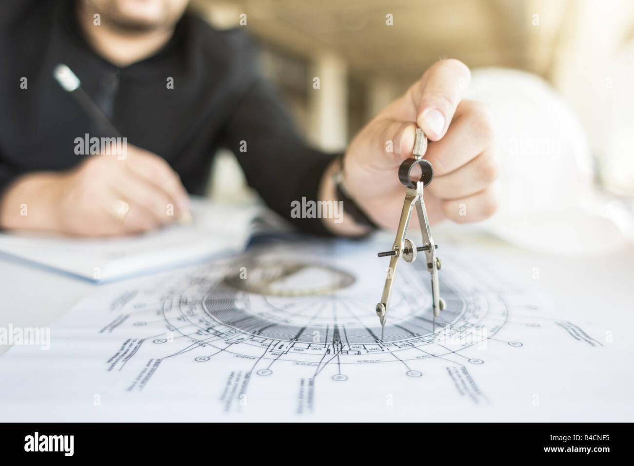 architect builder works at the table with drawings. Helmet, drawings, compasses in the workplace Stock Photo
