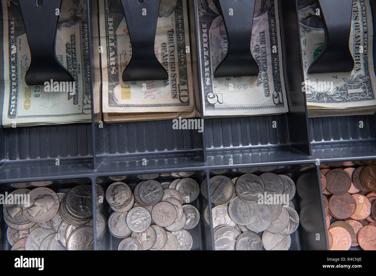An open cash register drawer showing US currency and coins. Stock Photo