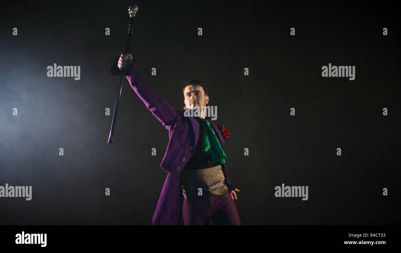 Showman points his cane up. guy in the purple camisole and the cylinder. Bright tailcoat, suit. Stock Photo