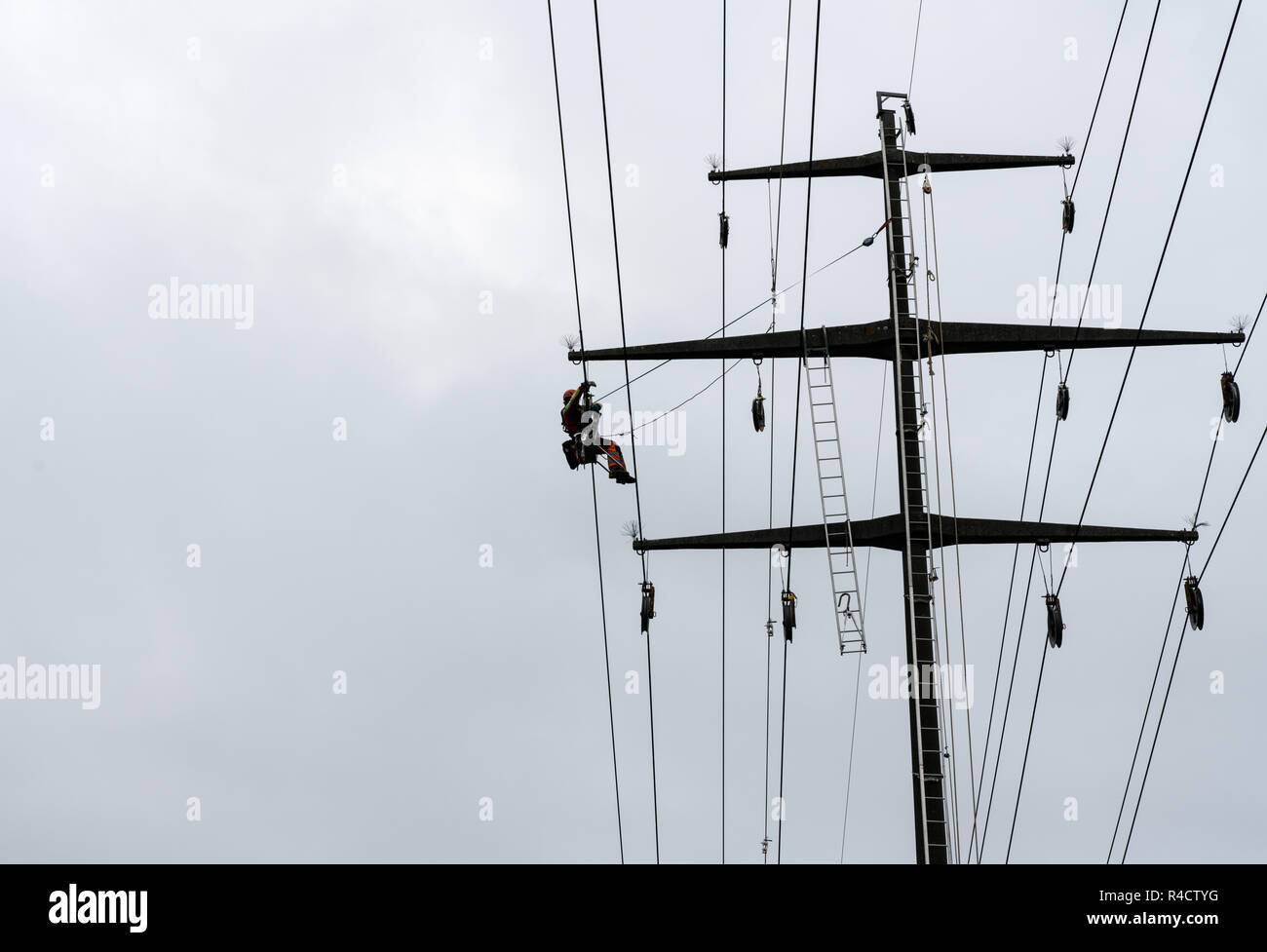 Working professional men on high voltage power lines high up on lattice