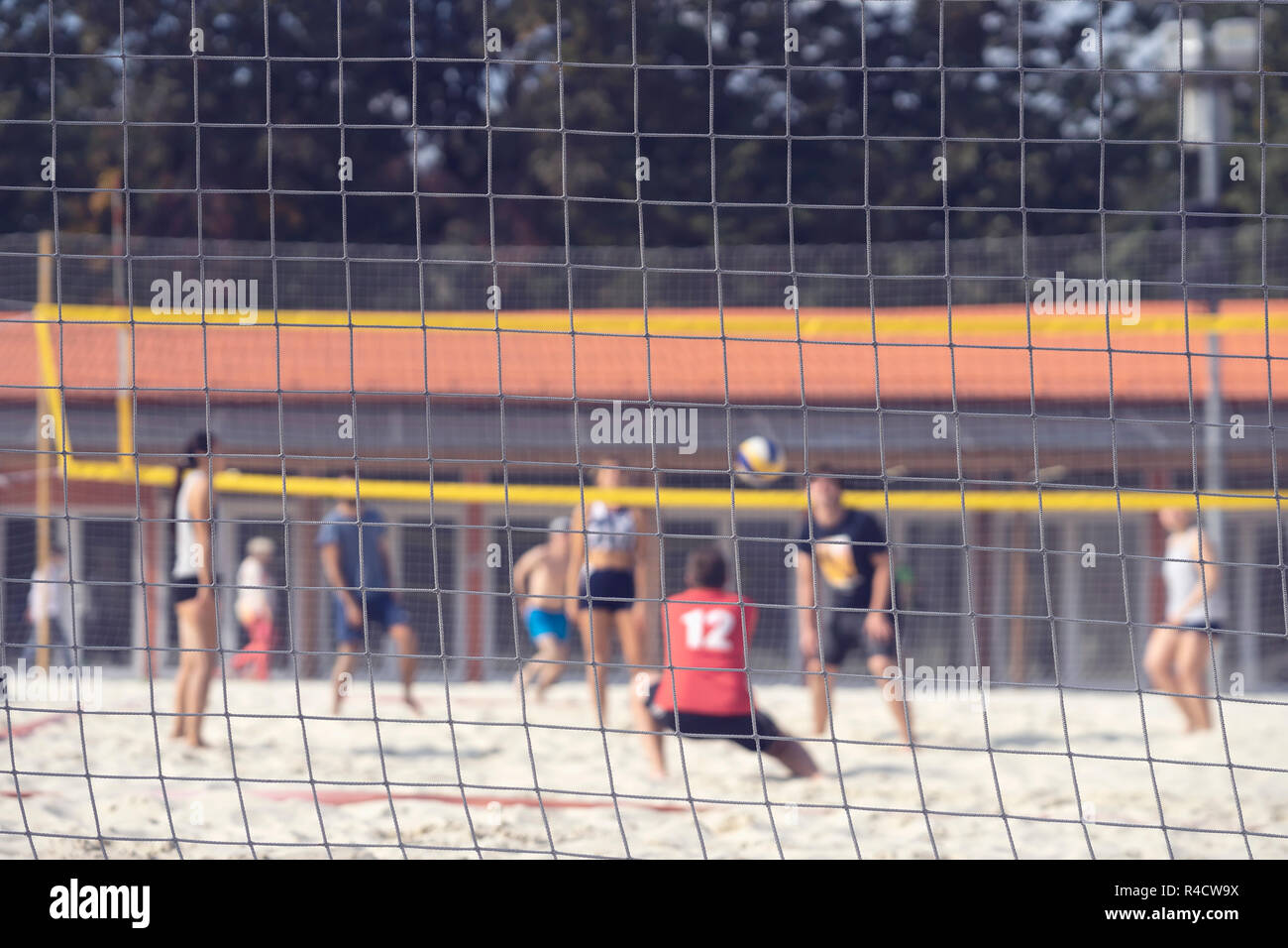 Group of young friends playing game volleyball on beach on summer day